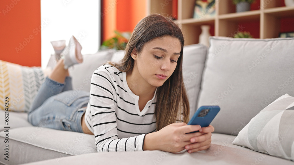 Young beautiful hispanic woman using smartphone lying on sofa at street Young beautiful hispanic woman using smartphone lying on sofa at street