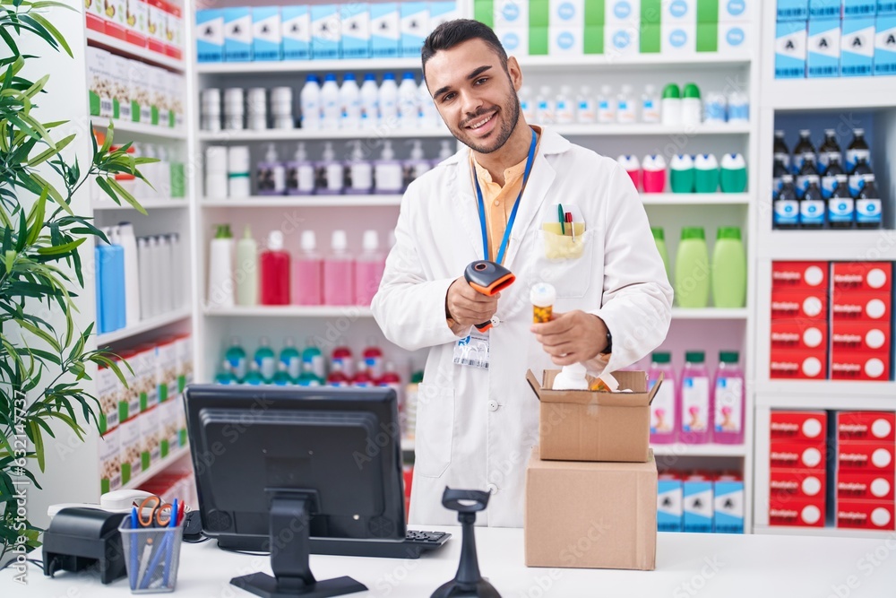 Young hispanic man pharmacist scanning pills bottle at pharmacy Young hispanic man pharmacist scanning pills bottle at pharmacy