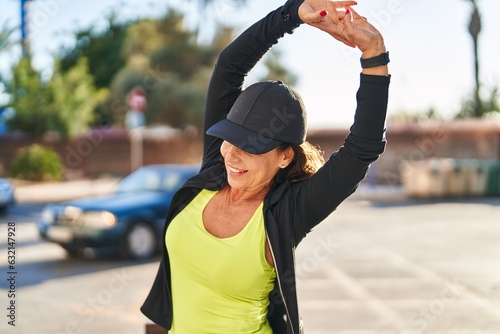 Middle age hispanic woman stretching arms outdoors