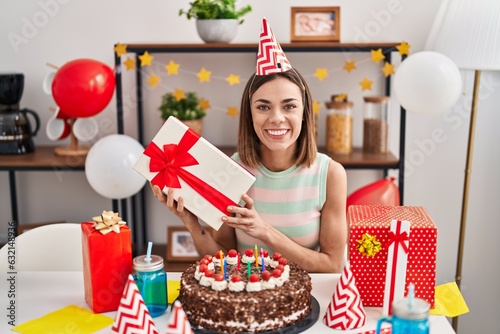 Photography Hispanic woman celebrating birthday with cake holding gift smiling with a happy and cool smile on face