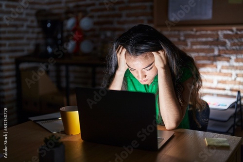 Fotografie Young teenager girl working at the office at night suffering from headache desperate and stressed because pain and migraine