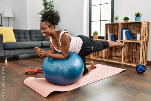 African american woman training abs exercise using fit ball at home photo
