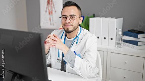 Hispanic man doctor using computer working at the clinic