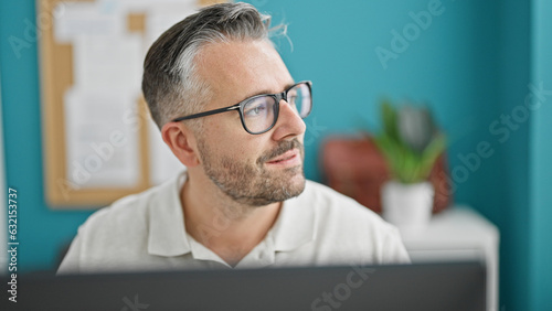 Grey-haired man business worker using computer thinking at the office