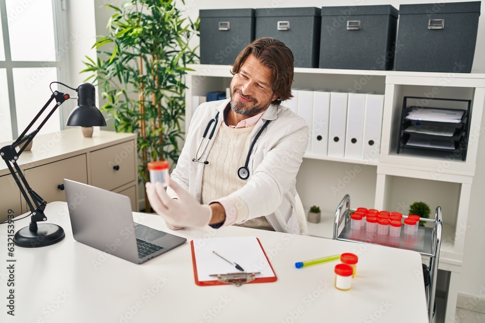 Middle age man doctor holding empty test tube at clinic Middle age man doctor holding empty test tube at clinic