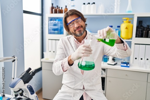 Middle age man scientist pouring liquid on test tube at laboratory
