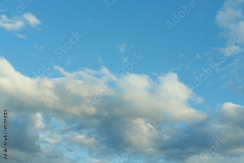Blue sky background with white fluffy cumulus clouds. Panorama of white fluffy clouds in the blue sky. Beautiful vast blue sky