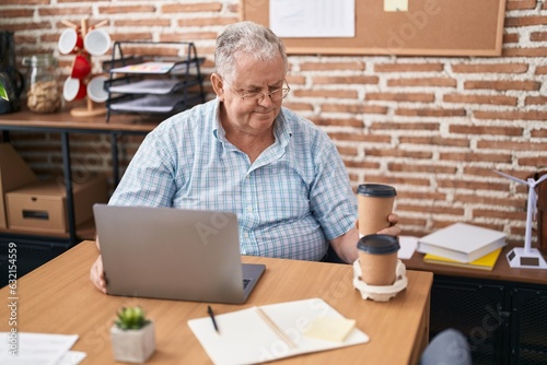 Middle age grey-haired man business worker holding take away coffee at office