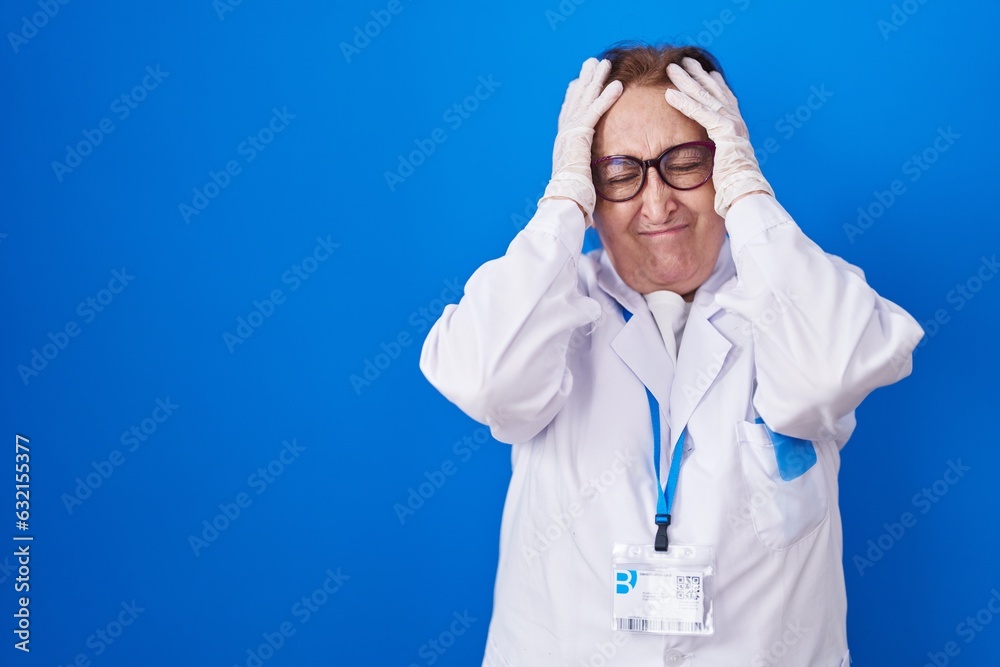 Senior woman with glasses wearing scientist uniform suffering from headache desperate and stressed because pain and migraine. hands on head. Senior woman with glasses wearing scientist uniform suffering from headache desperate and stressed because pain and migraine. hands on head.