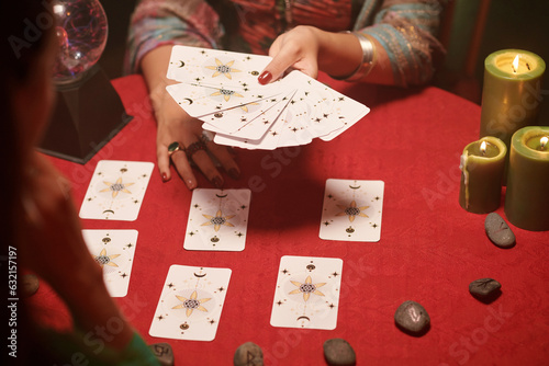 Hands of seer asking woman to choose cards from spread