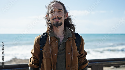 Young hispanic man tourist wearing backpack relaxed at seaside
