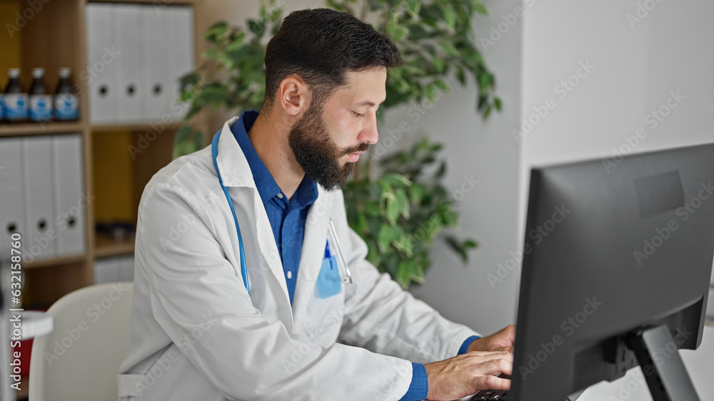 Young hispanic man doctor using computer working at the clinic