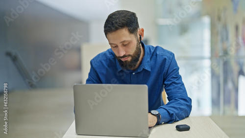 Young hispanic man business worker using laptop and earphones at the office