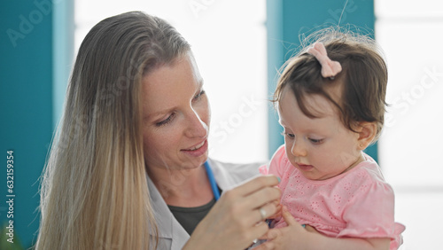 Mother and daughter playing with stethoscope at clinic