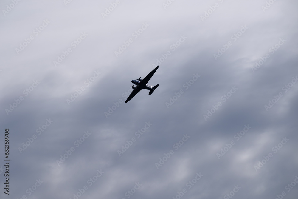 An old propeller passenger airplane flying against a cloudy morning sky. An old propeller passenger airplane flying against a cloudy morning sky.