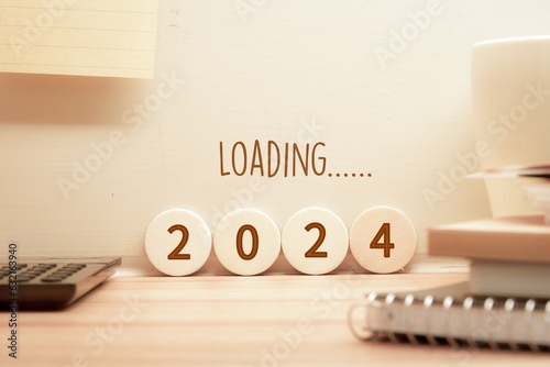 2024 loading inscription on wooden blocks and wall on study desk. New year start concept. photo