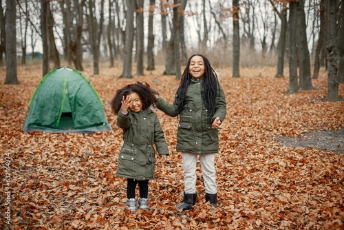 Two little black sisters playing near tent camping in the autumn forest