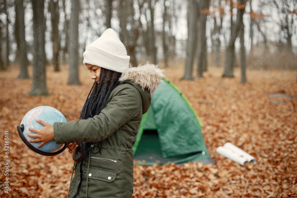 One little black girl holding a globe in tent camping in the autumn forest