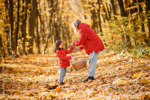 Mother and daughter walking and playing in autumn forest