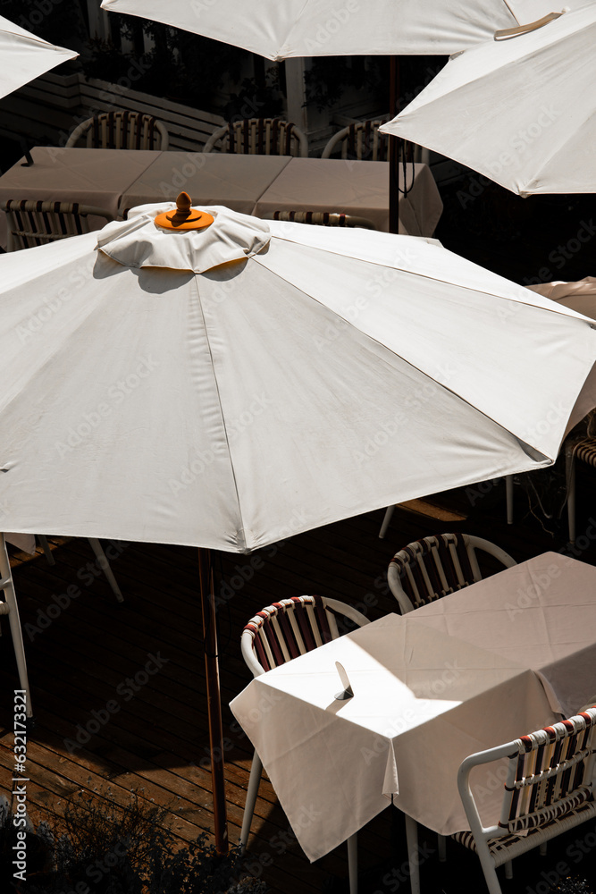 Cafe umbrellas, tables and chairs in sunlight