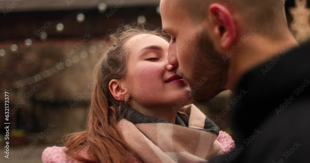 Close-up of the faces of a young couple in love kissing and hugging on the street on a gloomy autumn day. Close-up of the faces of a young couple in love kissing and hugging on the street on a gloomy autumn day.