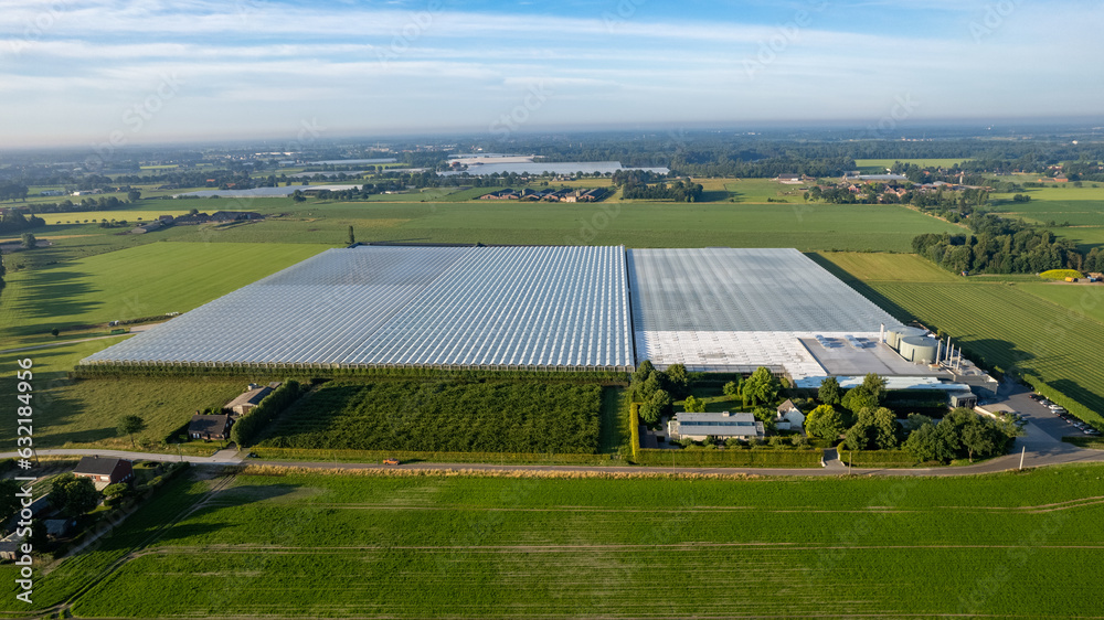 Obraz premium A captivating aerial photograph showcasing the cutting-edge world of agriculture, with modern industrial glasshouses standing prominently amidst vast and lush farm fields. This striking image captures