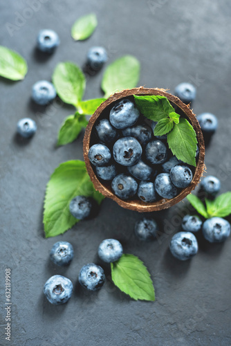 Freshly picked blueberries in coconut bowl on dark background. Healthy organic seasonal fruit background. Berries closeup