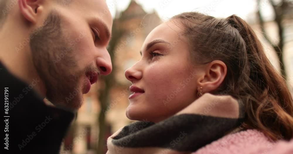Close-up of the faces of a young couple in love kissing and hugging on the street on a gloomy autumn day. Close-up of the faces of a young couple in love kissing and hugging on the street on a gloomy autumn day.