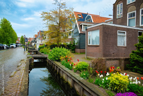 Fototapeta Naklejka Na Ścianę i Meble -  View of one of the streets of Volendam, with a small canal on its side, where there are walkways to access the houses. Netherlands