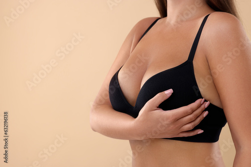 Woman with beautiful breast on beige background, closeup. Space for text