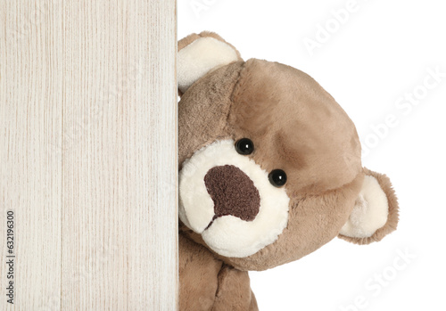 Cute teddy bear peeking out of wooden board on white background photo