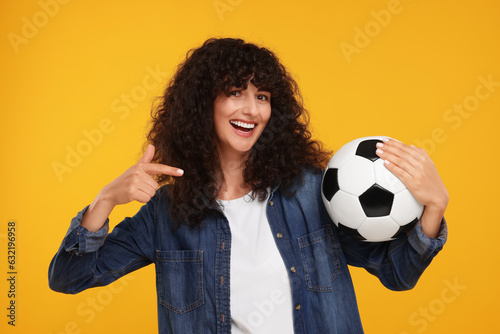 Happy fan showing soccer ball on yellow background © New Africa