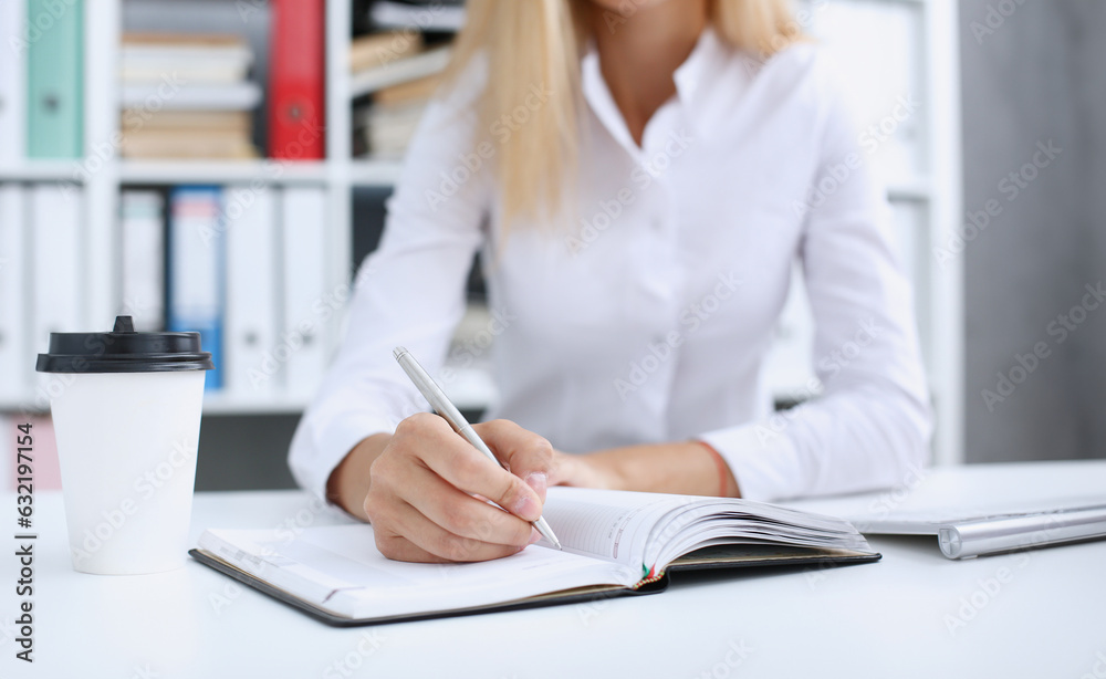 Female hand holding silver pen ready to make note in opened notebook sheet. Businesswoman coffee cup workspace make thoughts records at personal organizer white letter collar conference signature Female hand holding silver pen ready to make note in opened notebook sheet. Businesswoman coffee cup workspace make thoughts records at personal organizer white letter collar conference signature
