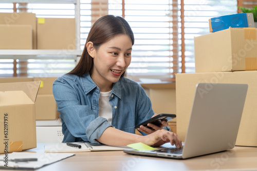 Young Asian woman owner of small online store packing customer orders in the home office.