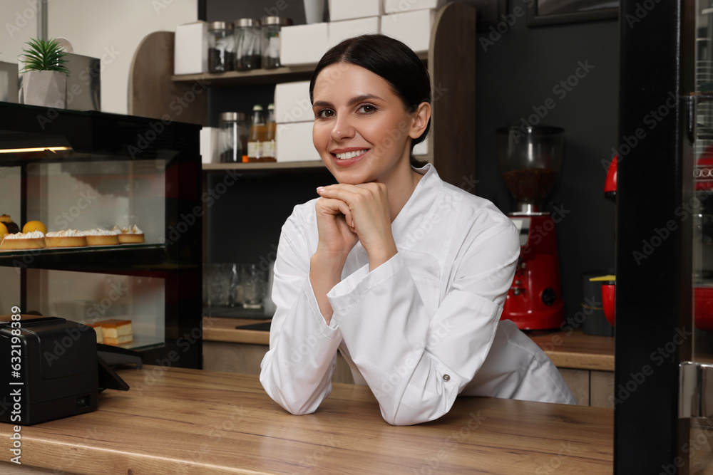 Portrait of happy baker at desk in her cafe