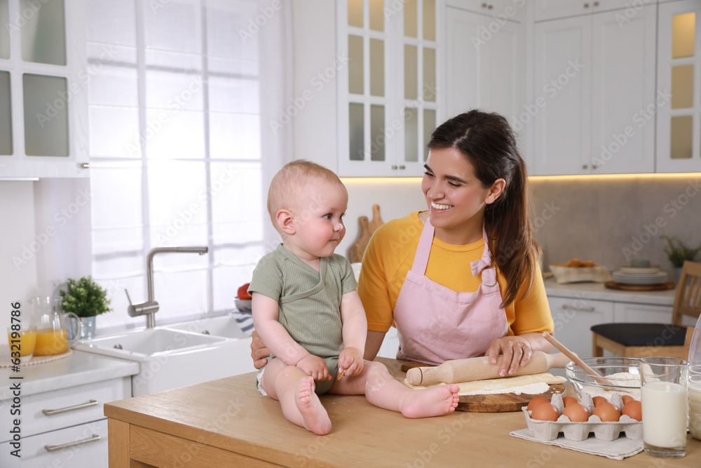 Happy young woman and her cute little baby cooking together in kitchen Happy young woman and her cute little baby cooking together in kitchen