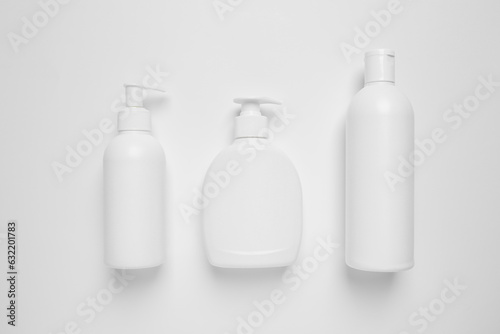 Bottles with different cosmetic products on white background, flat lay