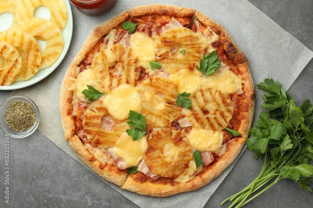Delicious pineapple pizza and ingredients on gray table, flat lay Delicious pineapple pizza and ingredients on gray table, flat lay