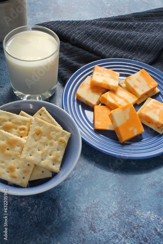 A snack of cheese and crackers with a glass of milk