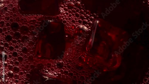 Pouring red soft drink into a glass full of ice cubes close-up slow motion shot. beverage and drink photo