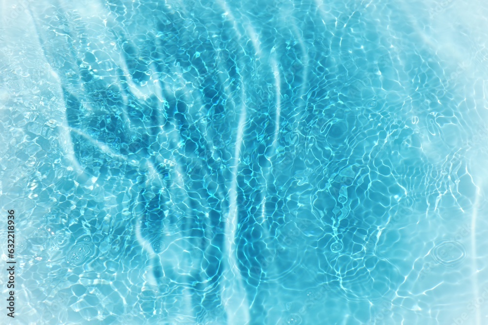Obraz premium Blue water with ripples on the surface. Defocus blurred transparent blue colored clear calm water surface texture with splashes and bubbles. Water waves with shining pattern texture background.