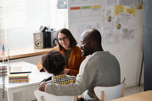 Фототапет Rear view of African American father talking to teacher about school success of