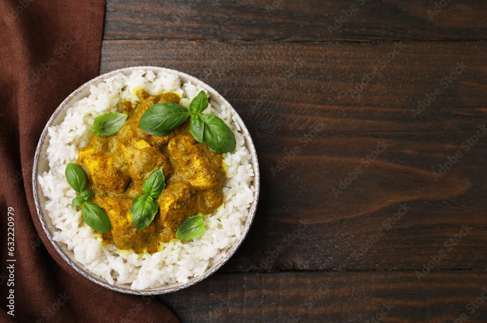 Delicious rice and chicken with curry sauce served on wooden table, top view. Space for text Delicious rice and chicken with curry sauce served on wooden table, top view. Space for text