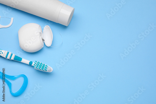 Tongue cleaner and other oral care products on light blue background, flat lay. Space for text