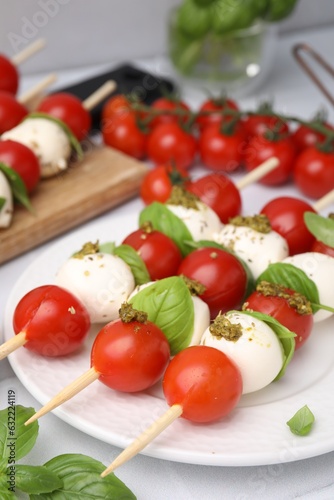 Caprese skewers with tomatoes, mozzarella balls, basil and pesto sauce on table, closeup. Space for text © New Africa