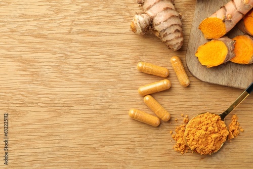 Aromatic turmeric powder, raw roots and pills on wooden table, flat lay. Space for text