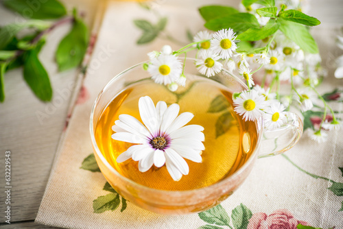 Chamomile flower tea in a glass cup and teapot  on a wooden table.