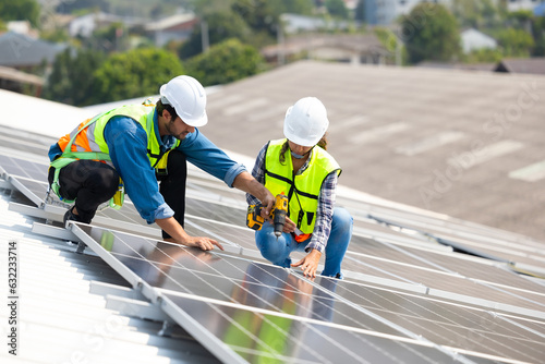 electrical engineering team man and woman worker Installing Solar Cell panels on Roof. Solar energy clean and green alternative energy. Unity and teamwork