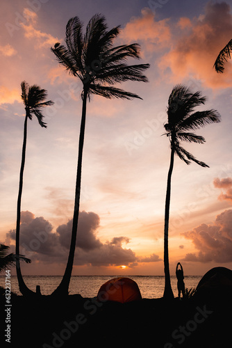 sunset at the beach with palm trees and camping