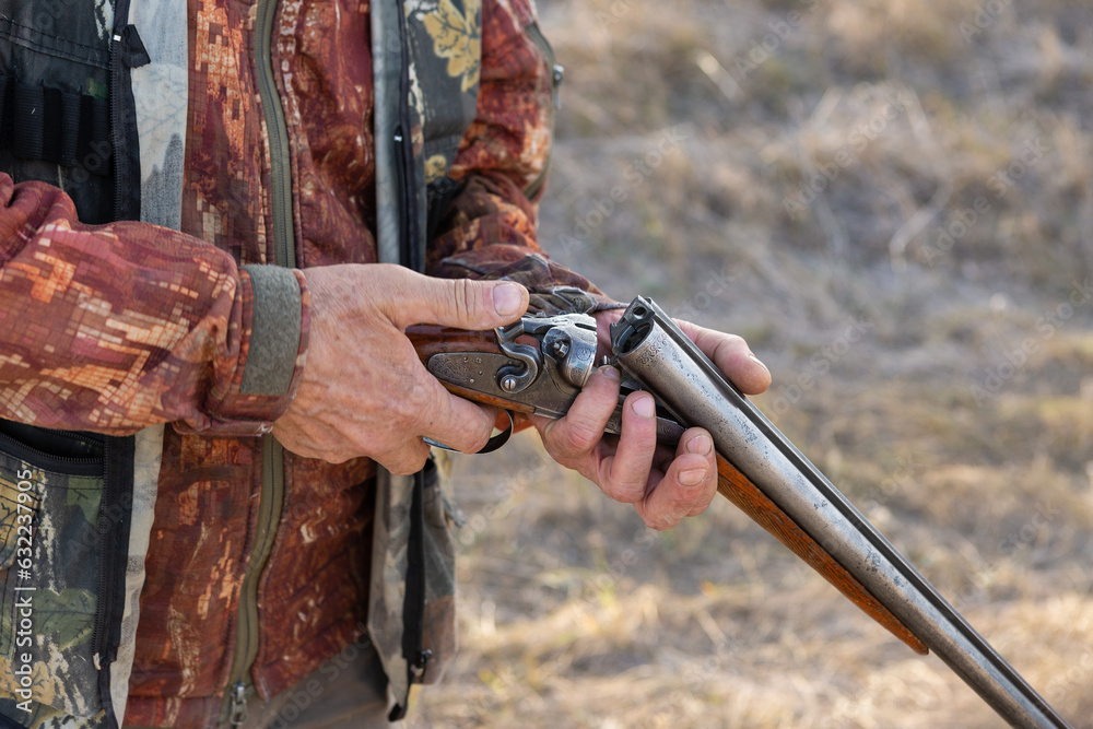 Fototapeta premium Midsection of man unloading shotgun while standing on field